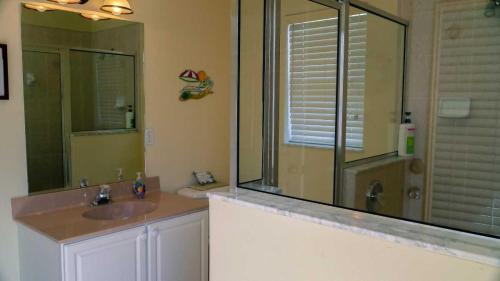a bathroom with a sink and a shower with a mirror at Heron's Nest in Port Saint Lucie