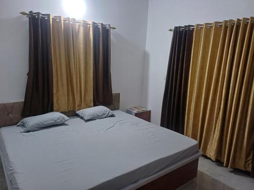 a bed with two pillows in a bedroom with curtains at Apte's Suparn in Ajra