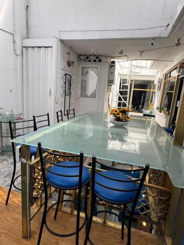 a glass table with blue chairs in a room at Casa Cristal in Mexico City
