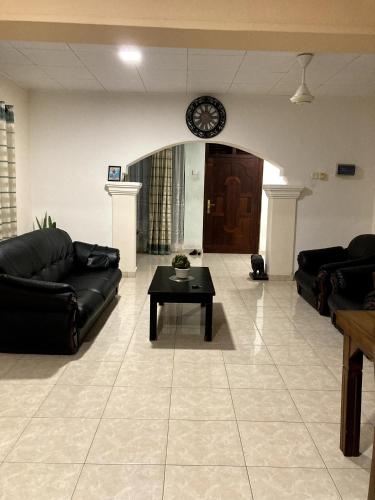 a living room with couches and a table and a clock at Serenity cove Dondra in Dondra West