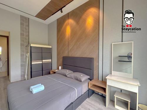 a bedroom with a large bed and a desk at Staycation Homestay 65 Liberty Grove Near Airport in Kuching