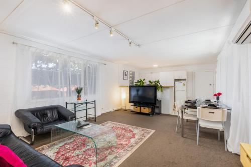 a living room with a couch and a table and a television at Cozy 2Bed& 1Bath Guest Suite surrounded by garden near Lake with Free parking and Wi-Fi in Yarralumla