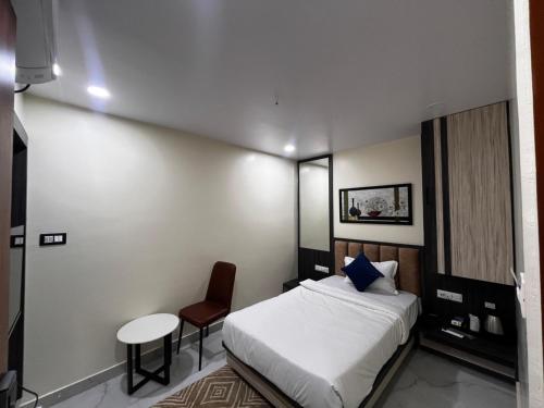 a bedroom with a bed and a table and a chair at Hotel soumya sarovar in Jagdalpur