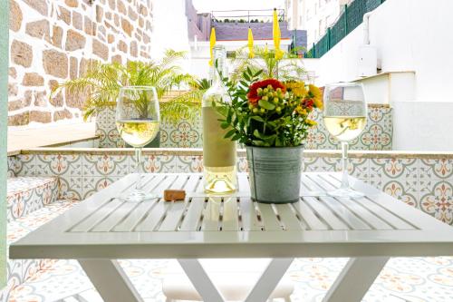 a table with two wine glasses and flowers on a balcony at Antero Quental Residence in Porto