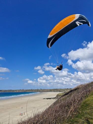 a person riding a parachute over a beach at La grange de Rose et François in Le Conquet