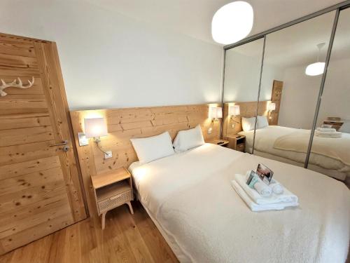 Cette chambre dispose d'un grand lit avec un miroir. dans l'établissement Les Gets - Appartement moderne avec grande terrasse, parking et 2 chambres - FR-1-598-185, aux Gets