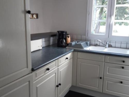 une cuisine avec des armoires blanches, un évier et une fenêtre dans l'établissement Maison confortable 5 pers - Forêt & plage à 500m - Animaux admis - FR-1-823-139, à Barbâtre