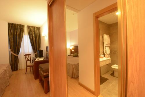 Habitación de hotel con cama, escritorio y espejo. en Hotel Campos de Castilla, en Soria