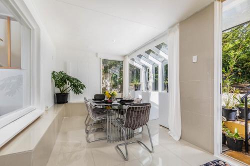 a dining room with a table and chairs and windows at Charming Garden Guest Suite in Leafy Yarralumla in Yarralumla