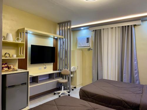 a bedroom with a bed and a desk with a television at GBF Premium Suite-Rm 207 Twin Hearts Residences 1 in Roxas City