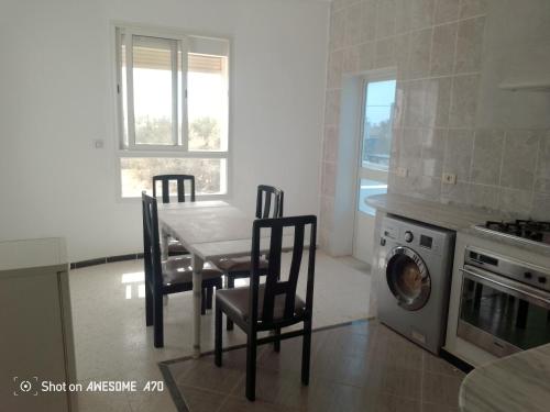 a kitchen with a table and chairs and a washing machine at Villa mimosas avec piscine in Taguermess