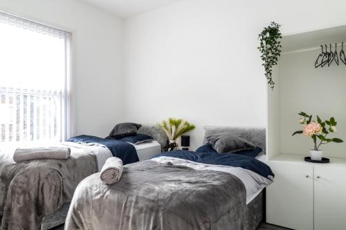 two beds in a bedroom with white walls at Eithad, Coop Live, Old Trafford with Free Parking in Manchester