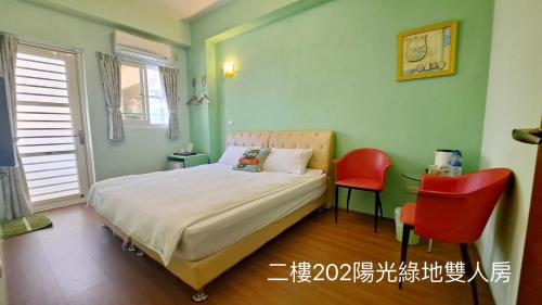 a bedroom with a bed and two red chairs at Dao Siang Hai B&B in Taitung City
