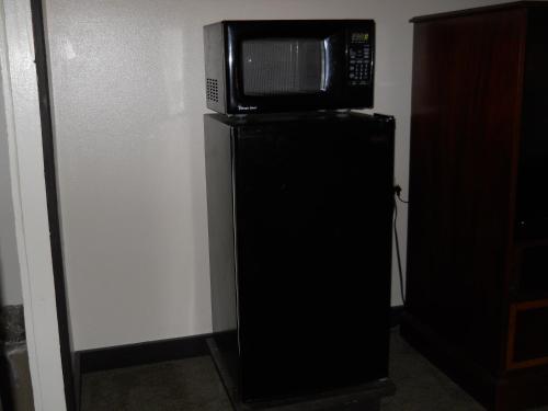 a microwave sitting on top of a black refrigerator at Value Inn Motel - Milwaukee Airport South in Oak Creek