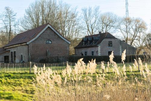 an old barn and a house in a field at Broekemmolen - Nature getaway & green spot in Bilzen