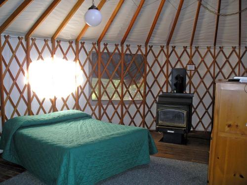 um quarto com uma cama e um fogão numa tenda em Yosemite Lakes Hillside Yurt 14 em Harden Flat