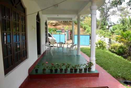 a porch of a house with a table and chairs at Ellagama Village Bungalow in Diyatalawa