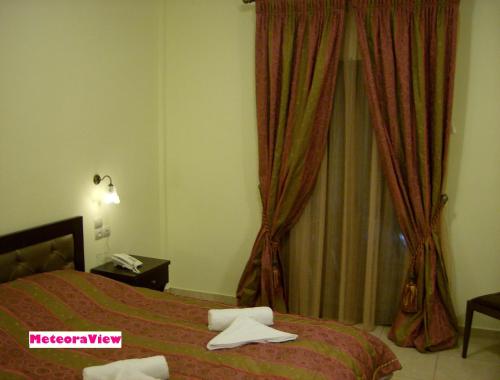 a bedroom with a bed and a window with curtains at Hotel Gogos in Kalabaka