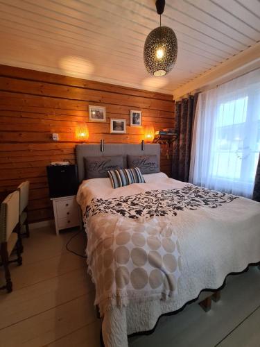 a bedroom with a bed in a room with wooden walls at Ainutlaatuinen huoneisto Vanhassa kyläkoulussa in Purola