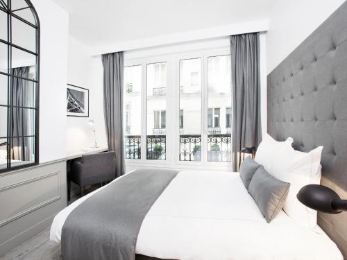 une chambre avec un grand lit avec une grande fenêtre dans l'établissement LivinParis - Luxury 3 Bedrooms Le Marais I, à Paris