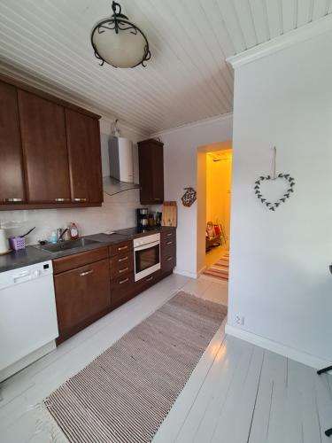 a kitchen with brown cabinets and a white floor at Ainutlaatuinen huoneisto Vanhassa kyläkoulussa in Purola