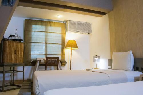 a bedroom with two beds and a table and a desk at Asmara Urban Resort & Lifestyle Village Powered by ASTON in Cebu City