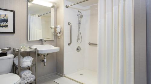 y baño con ducha, aseo y lavamanos. en Holiday Inn Palm Beach-Airport Conf Ctr, an IHG Hotel, en West Palm Beach
