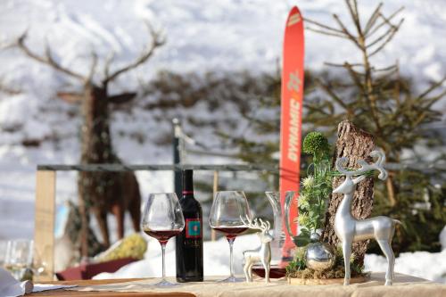 a table with two wine glasses and wine bottles at Hotel und Alpen Apartments mit Sauna - Bürglhöh in Bischofshofen