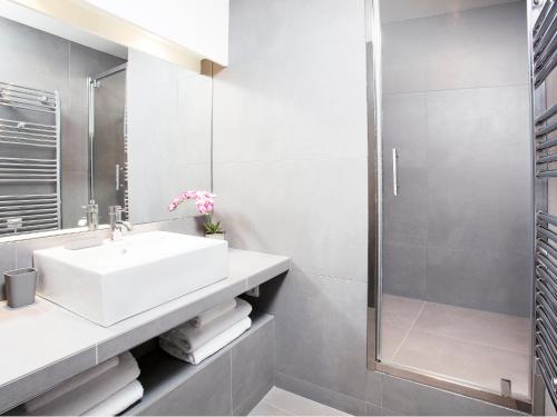une salle de bain blanche avec un lavabo et une douche dans l'établissement LivinParis - Luxury 3 Bedrooms Le Marais I, à Paris