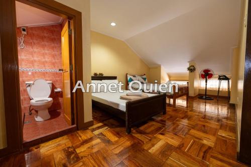 a bathroom with a bed and a toilet in a room at 4 Bedroom Log Cabin in Camp John Hay Baguio in Baguio