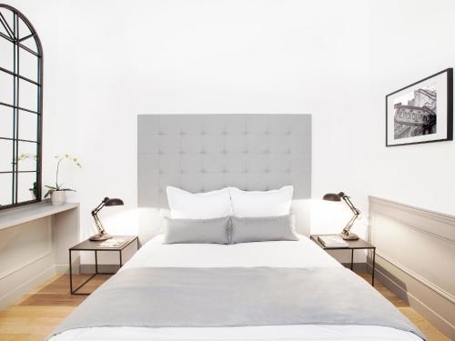 ein weißes Schlafzimmer mit einem großen Bett mit zwei Lampen in der Unterkunft LivinParis - Luxury 2 Bedrooms Le Marais I in Paris
