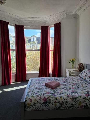 a bedroom with a bed with red curtains and a large window at Freedom Park Villas, Plymouth in Plymouth