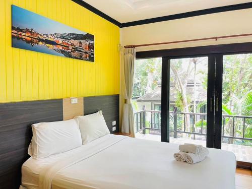 a bedroom with a bed with a yellow wall at สงขลาคีรี รีสอร์ท SongkhlaKeeree Resort in Ban Khao Rup Chang