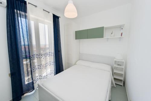 villetta rosa blu marina di modica في مارينا موديكا: غرفة نوم بيضاء بها سرير ونافذة