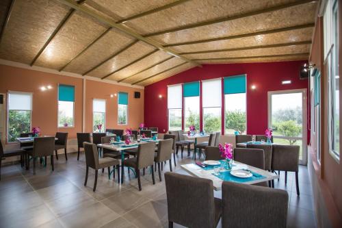 a dining room with tables and chairs and windows at La Terra Nostra in Korinthos