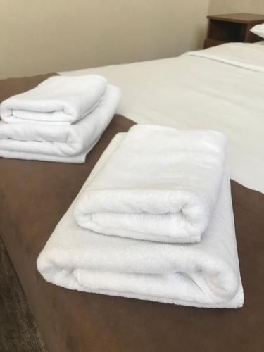 three white towels are stacked on a bed at Hotel LaMa 2 in Kyiv