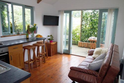 a living room with a couch and a kitchen with sliding glass doors at The Beech Hut - Peaceful countryside retreat in West Down