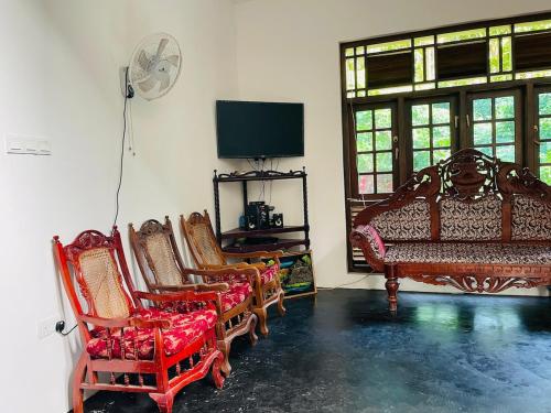 a living room with chairs and a tv and a fan at Mandara Villa Hiriketiya in Dickwella