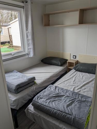 deux lits dans une chambre avec une fenêtre dans l'établissement ARDECHE, mobil home 6 personnes climatisé, à Lagorce