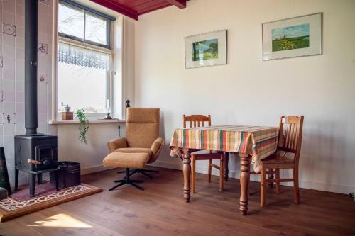 a dining room with a table and chairs and a stove at BnB Alde Hiemen Friesland in Terwispel