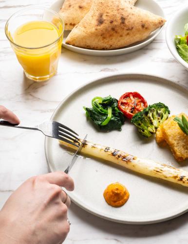 a person holding a knife and fork and a plate of food at NOHGA HOTEL AKIHABARA TOKYO in Tokyo