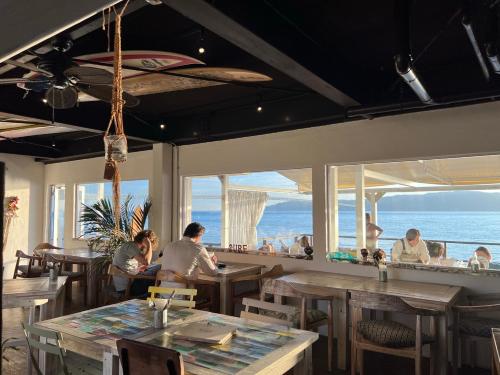 people sitting at tables in a restaurant with the ocean at BeachHouse Geragera in Kobe
