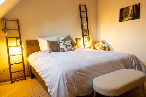 a bedroom with a white bed with a chair and shelves at Broekemmolen - Nature getaway & green spot in Bilzen