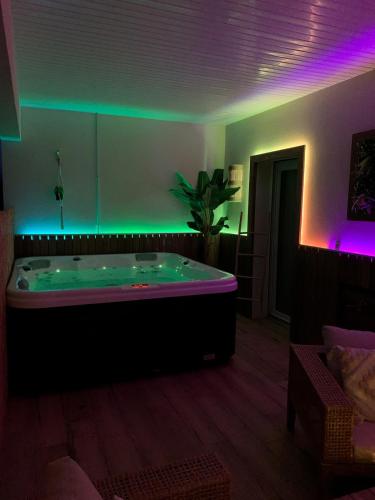 a room with a large bath tub with purple lights at La Terrasse Enchantée, Romance, Cosy et Jacuzzi in Belin-Beliet