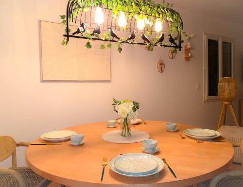 a dining room table with a chandelier at La Terrasse Enchantée, Romance, Cosy et Jacuzzi in Belin-Beliet