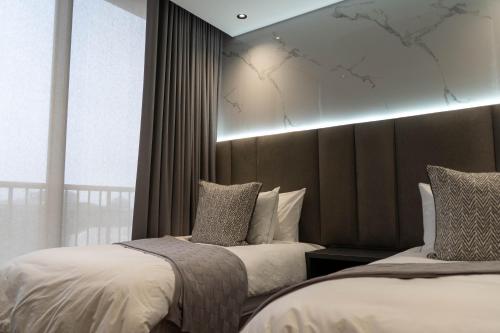 a bedroom with two beds and a large window at Prada Penthouse at On Park Century City in Cape Town