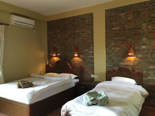 two beds in a room with a brick wall at Chautari Garden Resort in Sauraha