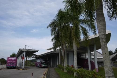 two buses parked at a bus station with palm trees at Moon Eleven Hostel Near Klia & Klia2 in Sepang