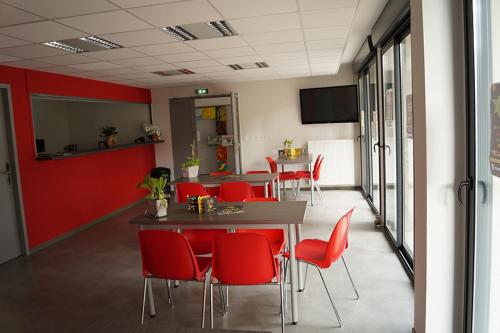 une salle de conférence avec des chaises rouges et une table dans l'établissement Centre International de Séjour - MJC, à Lézignan-Corbières