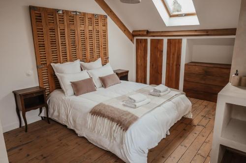 ein Schlafzimmer mit einem großen weißen Bett mit einem hölzernen Kopfteil in der Unterkunft Maison en bord de Dordogne in Bergerac